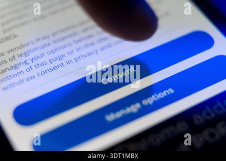 Close-up of a finger about to press a blue Consent button on a smartphone screen, concept for digital privacy, cookie policy, and user data agreement. Stock Photo