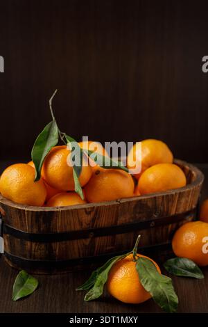 Tangerine mandarine with leaves in wooden box on dark background Stock Photo