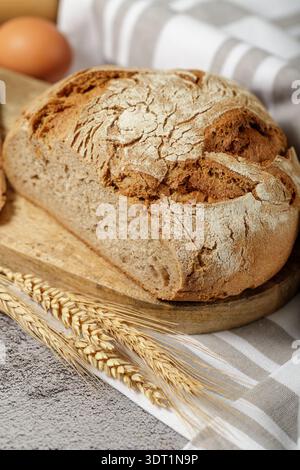 A fresh rye-wheat bread  closeup on a wooden board.  Background with lein towel Stock Photo