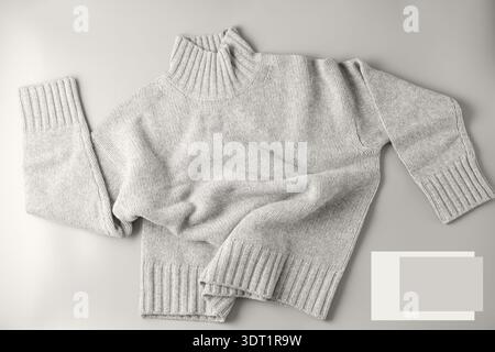 Soft sweater of light grey melange natural  mix merino wool and cashmere lying on neutral background. Autumn and winter pure wool clothing in trendy c Stock Photo