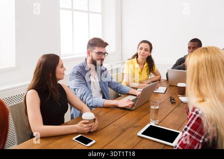 Group of People Having a Meeting in a Bright Room With Laptops and Drinks on a Table Stock Photo