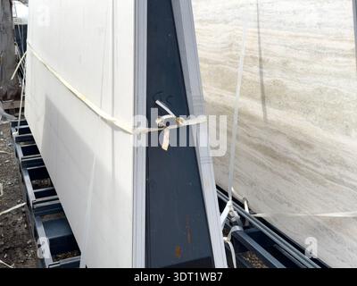 A warehouse setting with neatly stacked travertine marble slabs secured on metal racks, showcasing the natural texture and pattern of the stone in a w Stock Photo