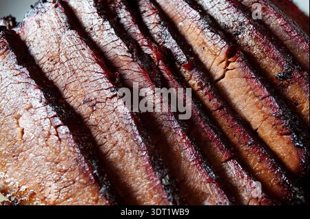 Close-up image of smoked barbecued beef brisket slices showcasing rich texture and dynamic highlights, emphasizing the succulent, tender quality of pe Stock Photo