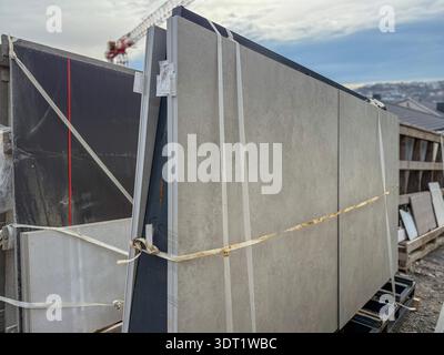 Large travertine and marble slabs are neatly stacked and secured with straps in a warehouse setting. The slabs are ready for shipment or installation Stock Photo