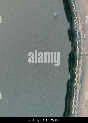 Frozen icy patterns on lake shoreline captured by drone during winter Stock Photo
