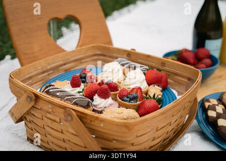 Picnic basket filled with fruit tarts and sweet treats Stock Photo