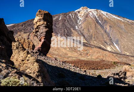 Scenic view of the famous Roque Cinchado rock formation and snow-capped Mount Teide volcano in Teide National Park, Tenerife, Canary Islands, Spain. The landscape features rugged volcanic rocks. Stock Photo