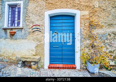 Charming blue wooden door on a historic adobe house in Comano Stock Photo