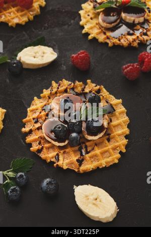 Creative Waffle Collection With Fruits and Sauce Arranged on a Dark Surface Stock Photo