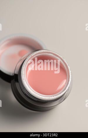Close-up of a gel nail extension product in a jar, featuring smooth pink polish. Ideal for adding vibrant color and durability to nails at salons or h Stock Photo