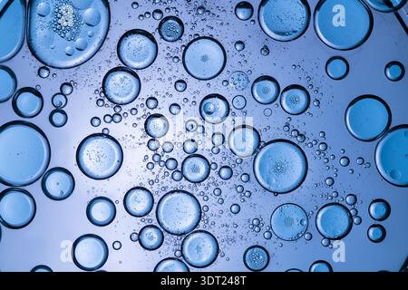 Macro photograph of blue bubbles of varying sizes on a liquid surface, creating a textured and intricate background. The close-up detail emphasizes th Stock Photo