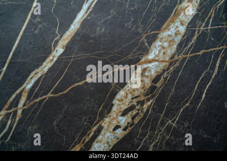 Natural stone pattern imitating marble with intricate brown and white veining on a dark background. Ideal for design projects requiring a touch of ele Stock Photo