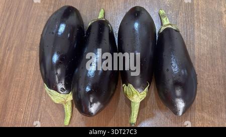 Fresh Whole Eggplants with Dew Drops on Wooden Surface Stock Photo