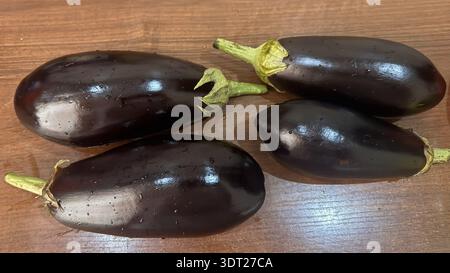 Fresh Whole Eggplants with Dew Drops on Wooden Surface Stock Photo