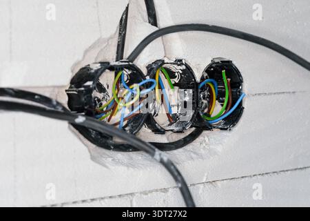 Boxes with cables for electric sockets installed in new house building empty wall Stock Photo