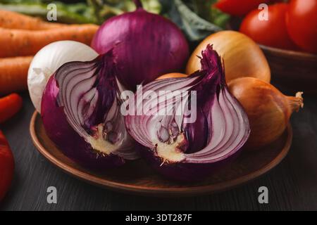 Collection of Sliced Onions and Vegetables on a Wooden Plate With Other Fresh Produce in View Stock Photo