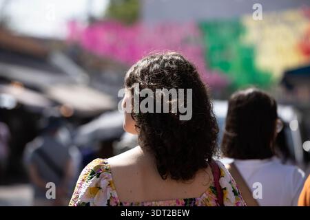 Woman exploring in outdoor market, shoulder skin and hair texture, rear view, at Chatuchak Market. Stock Photo