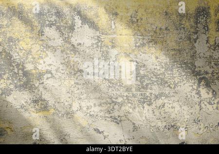 Horizontal close-up f an old beige plaster wall with peeling texture and cracks, lit by sunlight creating dynamic diagonal shadows, copy space Stock Photo