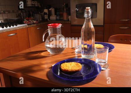 Kitchen table set with two plates of food, a water bottle, and pitcher under warm light Stock Photo