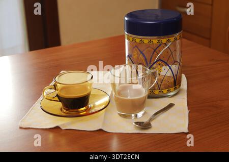 Coffee cup with espresso, milk, and sugar on a napkin on a wooden table Stock Photo