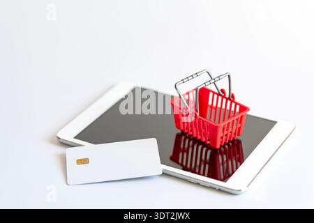 Minimalist still life of white credit card and shopping cart on isolated digital tablet on white background, with space for text. Concept of online pa Stock Photo