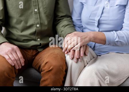 Couple holding hands in a gentle close-up, showing comfort, trust and emotional support between partners intimate connection and caring companionship in everyday life Stock Photo