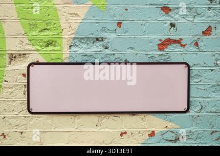 Blank sign with space for text on colourful painted brick wall Stock Photo