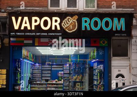 LONDON - DECEMBER 5, 2025: Vapor Room Willesden Green NW2 – Illuminated Vape Shop with International Flags Stock Photo