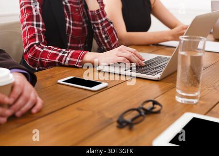 Group of People Working on Laptops at a Wooden Table in an Office Setting During the Day Stock Photo