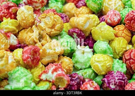 Pile of sweet popcorn coated in vibrant, multi‑colored glaze, creating a bright and eye‑catching snack display. Close-up shot, abstract food backgroun Stock Photo