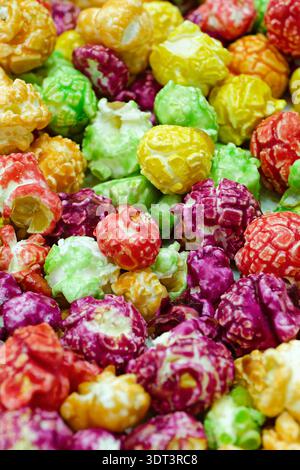 Pile of sweet popcorn coated in vibrant, multi‑colored glaze, creating a bright and eye‑catching snack display. Close-up shot, abstract food backgroun Stock Photo