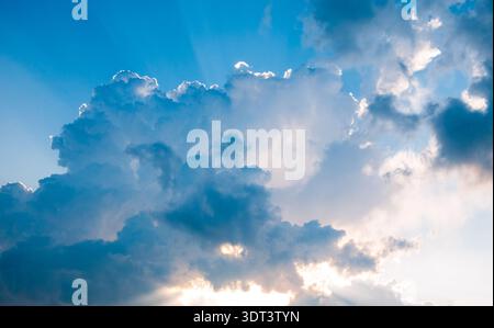 Dramatic clouds with sun rays breaking through blue sky Stock Photo