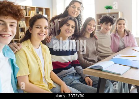 Cheerful students with teacher in classroom, united teens portrait for teamwork Stock Photo