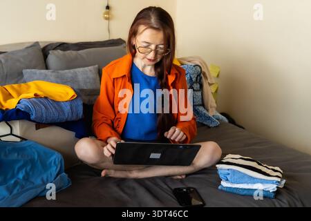 Woman analyzing online clothing sales data on tablet managing home based micro business through digital analytics strategy performance tracking and Stock Photo