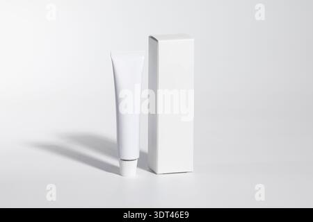 Mockup of a white box and tube of cream or ointment, parapharmacy product, front side view, white background, isolated Stock Photo