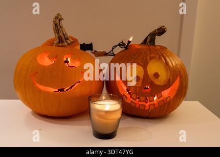 Two carved Halloween jack-o-lantern pumpkins with a candle on a white table in Vancouver Canada Stock Photo