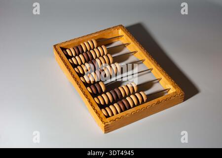 Vintage abacus on a wooden background. A simple mechanical device, a counting board, for performing arithmetic calculations. Stock Photo