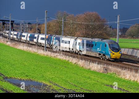 Avanti Pendolino tilting train named City of Edinburgh on the West Coast main line at Winwick beneath threatening dark skies full of rain. Stock Photo
