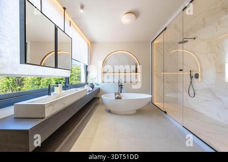 an image of a luxury illuminated bathroom with freestanding bathtub and shower room in mediterranean holiday home Stock Photo