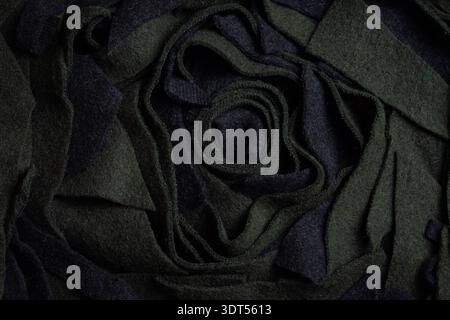 Black wool scraps arranged in a rose‑like spiral highlight textile waste, crafting creativity, and eco‑friendly upcycling. Stock Photo