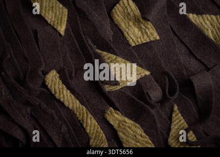 Dark brown wool fabric mixed with olive green scraps creates a textured pattern representing textile waste, crafting leftovers, and sustainable fabric Stock Photo