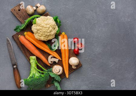 Fresh Vegetables Arranged on a Wooden Board With a Knife and Gray Background Stock Photo