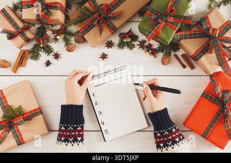 Planning Gift Ideas With a Notepad Near Decorated Presents During the Holiday Season Stock Photo