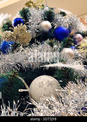 Decorated Christmas tree with blue and silver baubles, shiny tinsel, festive ornaments and green pine branches. Classic winter holiday background with Stock Photo