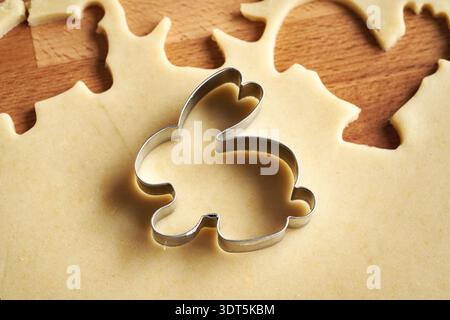 Cutting out bunny shapes from rolled out pastry dough - preparation of homemade Linzer Easter cookies Stock Photo