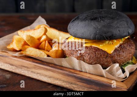 Unique Burger Served With Golden Fries on a Wooden Board in a Casual Setting Stock Photo