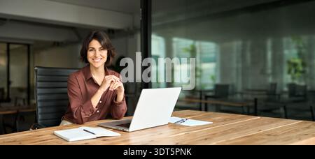 Smiling Hispanic young woman entrepreneur looking at camera at work. Portrait Stock Photo