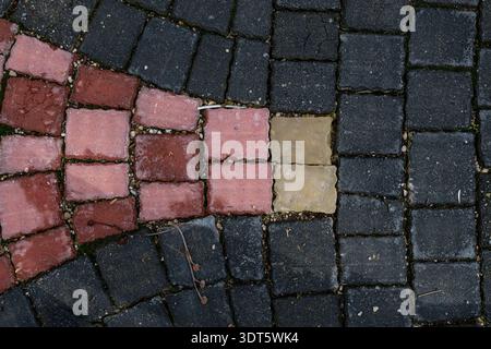 Close-up of interlocking stone pavement pattern with red, grey, and yellow bricks. Urban design and architectural outdoor flooring detail. Stock Photo