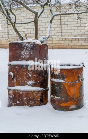 Rusty metal barrels covered with fresh winter snow Stock Photo