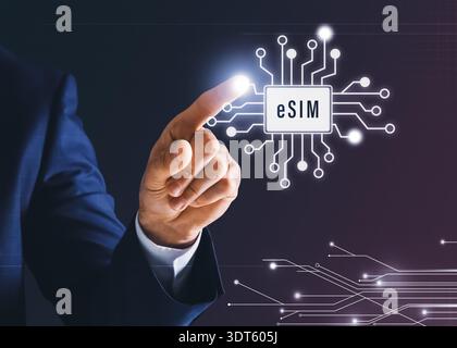 Businessman activating eSIM microchip on virtual screen, closeup. Dark background with circuit board pattern Stock Photo